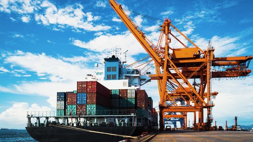 Foto eines großen Frachtschiffs beim Entladen und Beladen einer Containerladung im Hafenterminal.