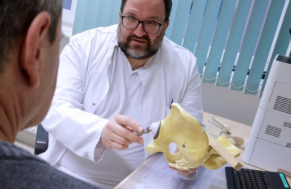 Dr. Henrik Naumburger erklärt einem Patienten im Endoprothetik-Zentrum am Modell einer Hüfte den Eingriff.