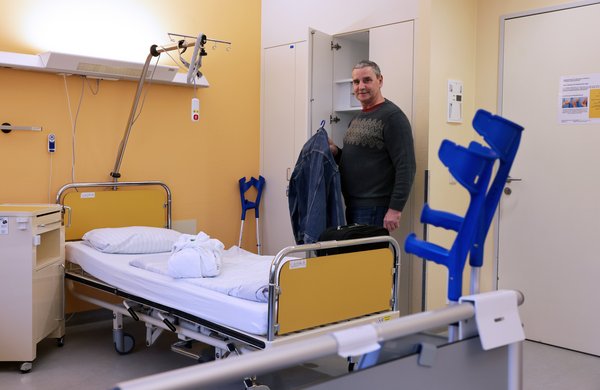 Ein Patient steht vor dem Kleiderschrank in einem Patientenzimmer im Achenbach-Krankenhaus Königs Wusterhausen.